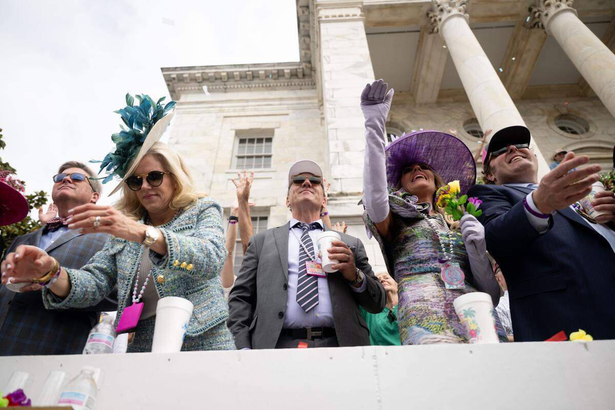 Members of the crowd cheer as they reach out to catch throws from floats driving down Lameuse Street.