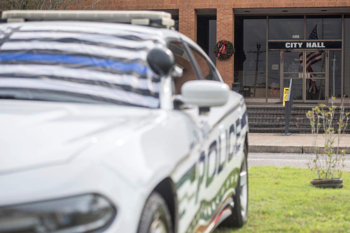 The American flag flies at half staff over a police car with a thin blue line flag outside the Bay St. Louis Police Station in honor of officers Steven Robin and Brandon Estorffe who were killed in the line of duty on Wednesday, Dec. 14, 2022.
