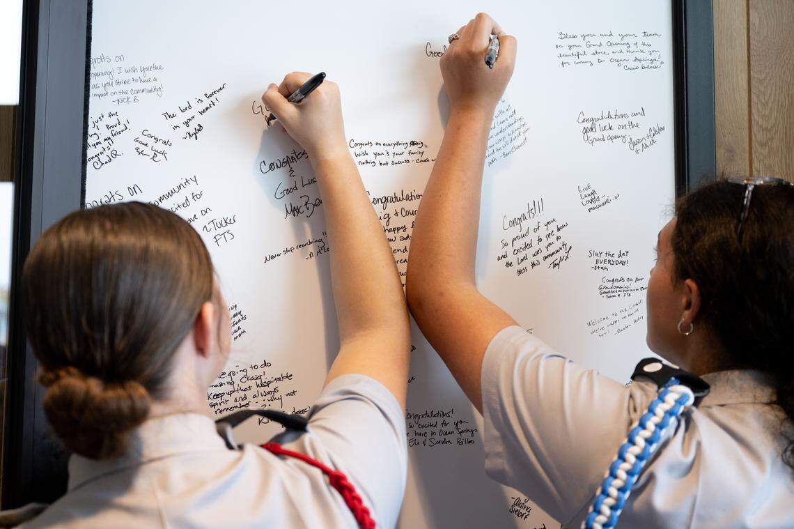 Ocean Springs JROTC members write welcome messages on a white board at the entrance of the new restaurant.
