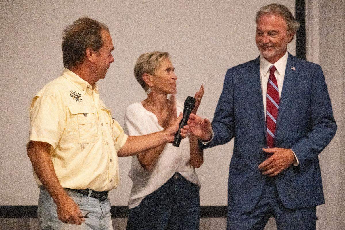 Mayor Billy Hewes passes Hugh Keating a microphone at an election party for Keating at Centennial Plaza in Gulfport on Tuesday, June 3, 2025. Keating is projected to win the mayoral race.