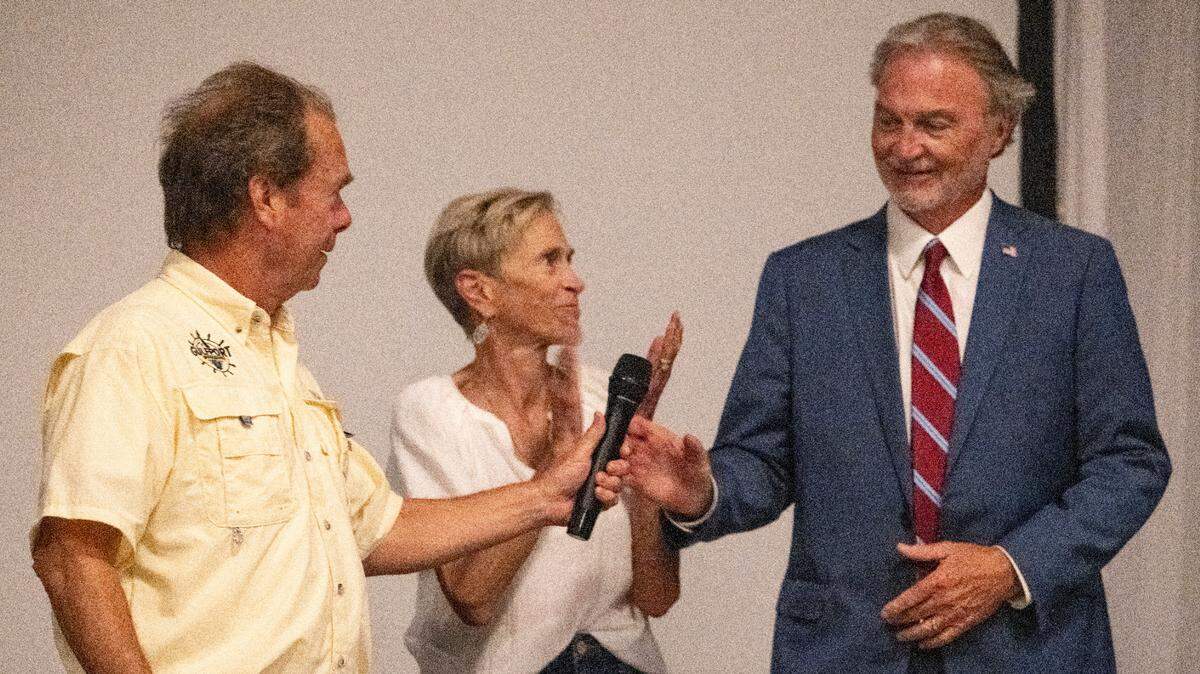 Mayor Billy Hewes passes Hugh Keating a microphone at an election party for Keating at Centennial Plaza in Gulfport on Tuesday, June 3, 2025. Keating won the mayor’s race.