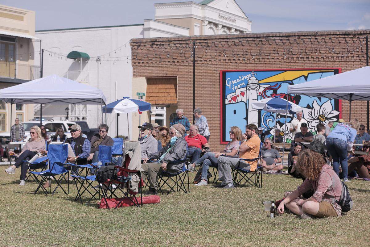 People listen to live music at the grand opening event for The District Green off Howard Avenue in Biloxi on Friday, March 5, 2021.