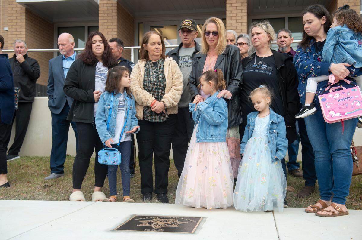 Members of Steven Robin’s family remove a sheet covering a metal star during a ceremony dedicating commemorative stars in honor of Sergeant Steven Robin and Officer Branden Estorffe outside the new Bay St. Louis Police Department in Bay St. Louis on Thursday, Dec. 14, 2023. Estorffe and Robin were killed on Dec. 14, 2022 by a local veterinarian when they responded to a call at a Motel 6.