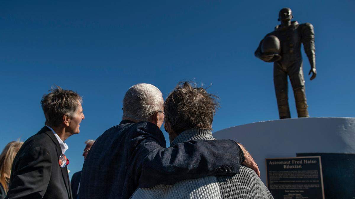 Apollo 13 astronaut Fred Haise Jr., center, hugs Mary Ott Tremmel Davidson, who sculpted the statue, as the new statue honoring Haise Jr. is unveiled at Biloxi Beach in Biloxi on Sunday, Feb. 13, 2022.