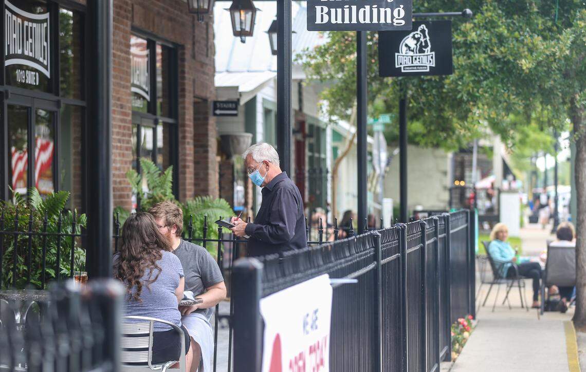 A masked waiter at Charred in Ocean Springs takes a couples order on their patio Saturday, May 9, 2020.