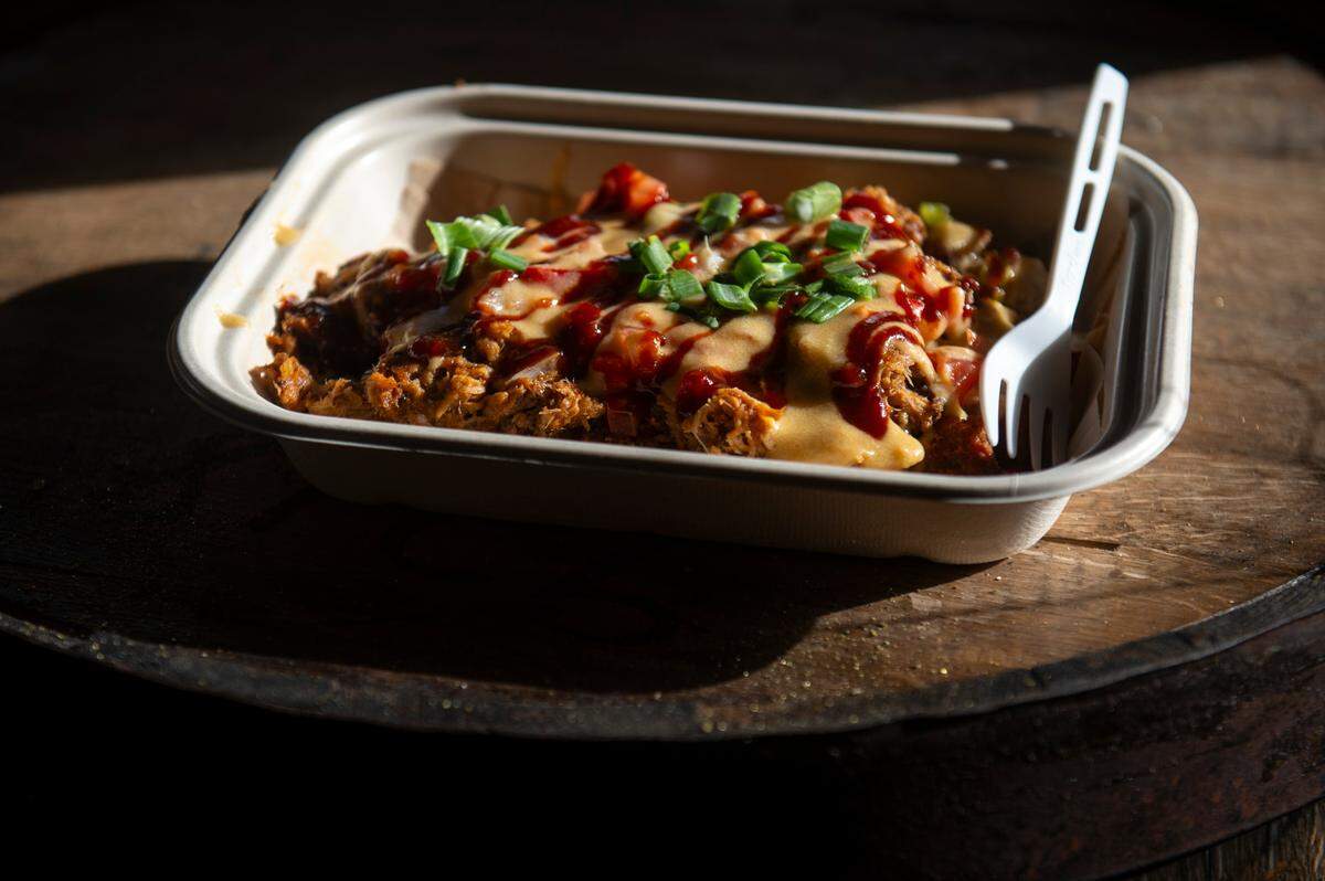 The loaded totchos, a dish of homemade tater tots topped with beer cheese, RC Cola barbecue sauce, onions, peppers, tomatoes, green onions, pulled pork and candied jalapeños, at The Garage at Cash Alley in Ocean Springs on Friday, Dec. 13, 2024.