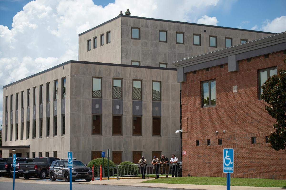 Members of law enforcement watch protestors from the Jackson County Courthouse building as a hearing in a chancery court case involving Heather Wyatt takes place on Thursday, July 18, 2024.