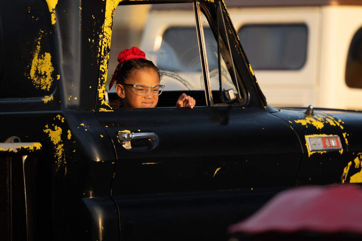 A child looks out the window of a vintage truck.