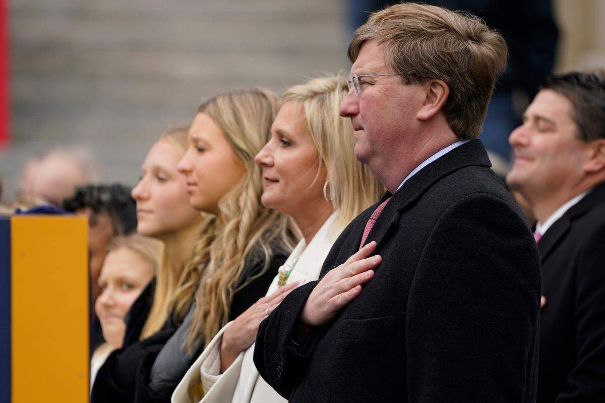 Mississippi Gov. Tate Reeves, right, and his wife Elee Reeves, second from right, stand at attention with their daughters during the playing of the National Anthem.