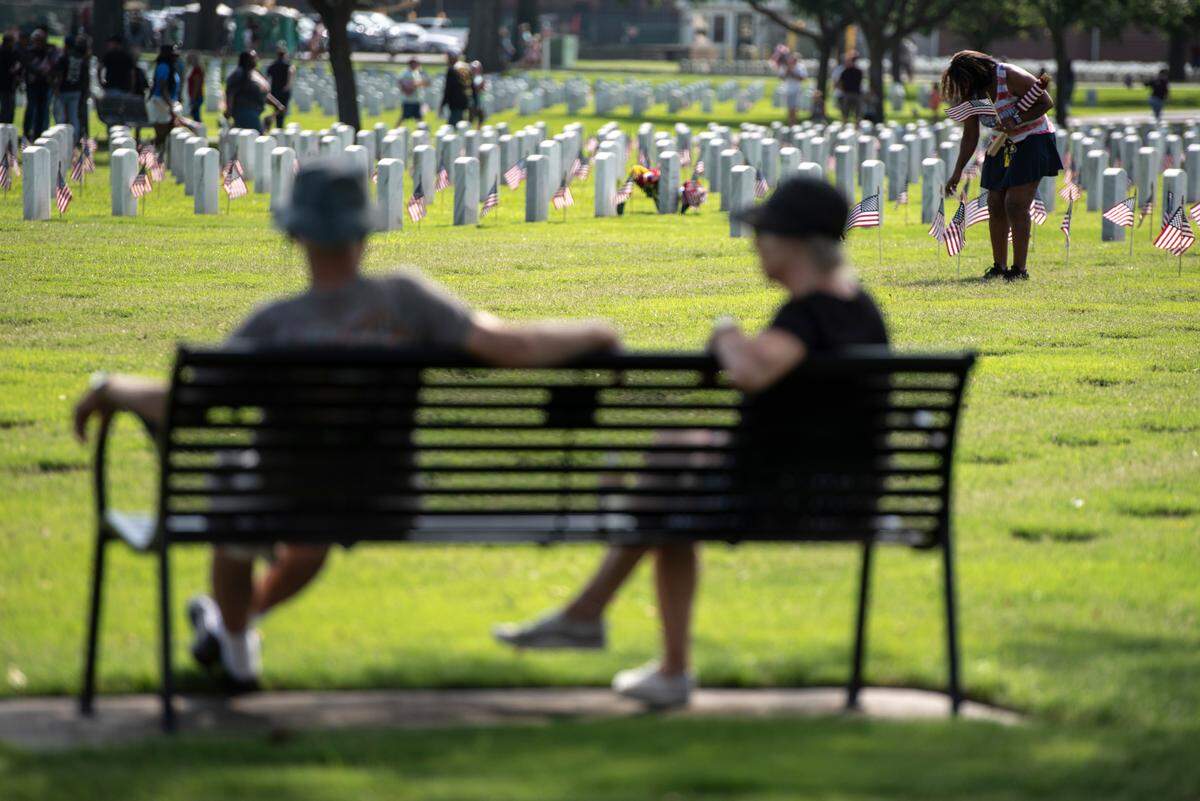 Volunteers help place thousands of tiny American flags on the graves of American service members at Biloxi National Cemetery in Biloxi ahead of Memorial Day on Saturday, May 25, 2024.