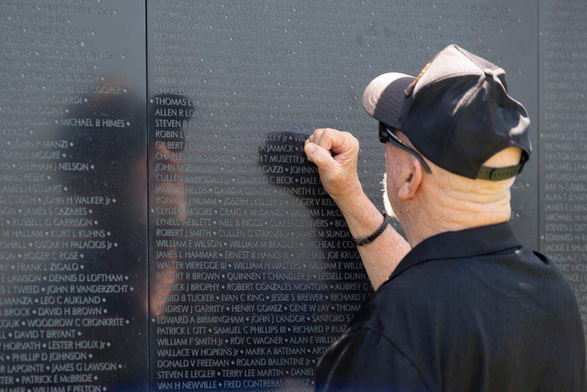 Jerry Delahoussaye taps his fist against The Wall That Heals, a traveling three-quarter scale replica of the Vietnam Veterans Memorial in D.C., while it is on display at the D’Iberville Sports Complex in D’Iberville on Thursday, April 10, 2025. Delahoussaye, a Vietnam veteran, has friends whose names are on the wall.