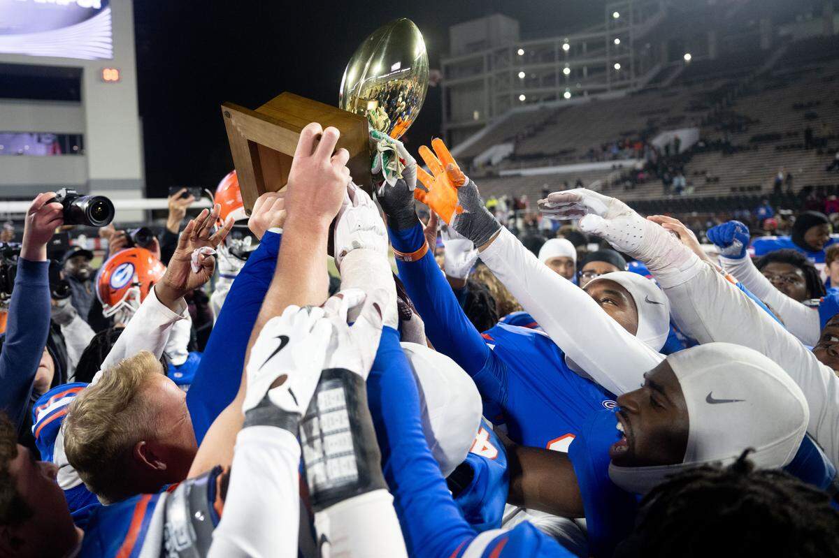 Gulfport players hoist the championship trophy Saturday after defeating Tupelo, 21-20.