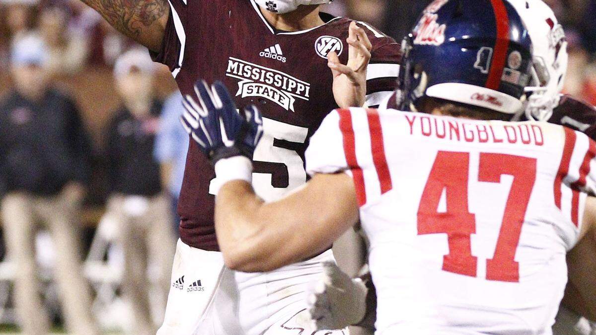 Mississippi State quarterback Dak Prescott (15) attempts a pass over the defense of Ole Miss defensive end John Youngblood (47) in an NCAA college football game in Starkville, Miss., Saturday, Nov. 28, 2015. No. 19 Mississippi won, 38-27. (AP Photo/Rogelio V. Solis)