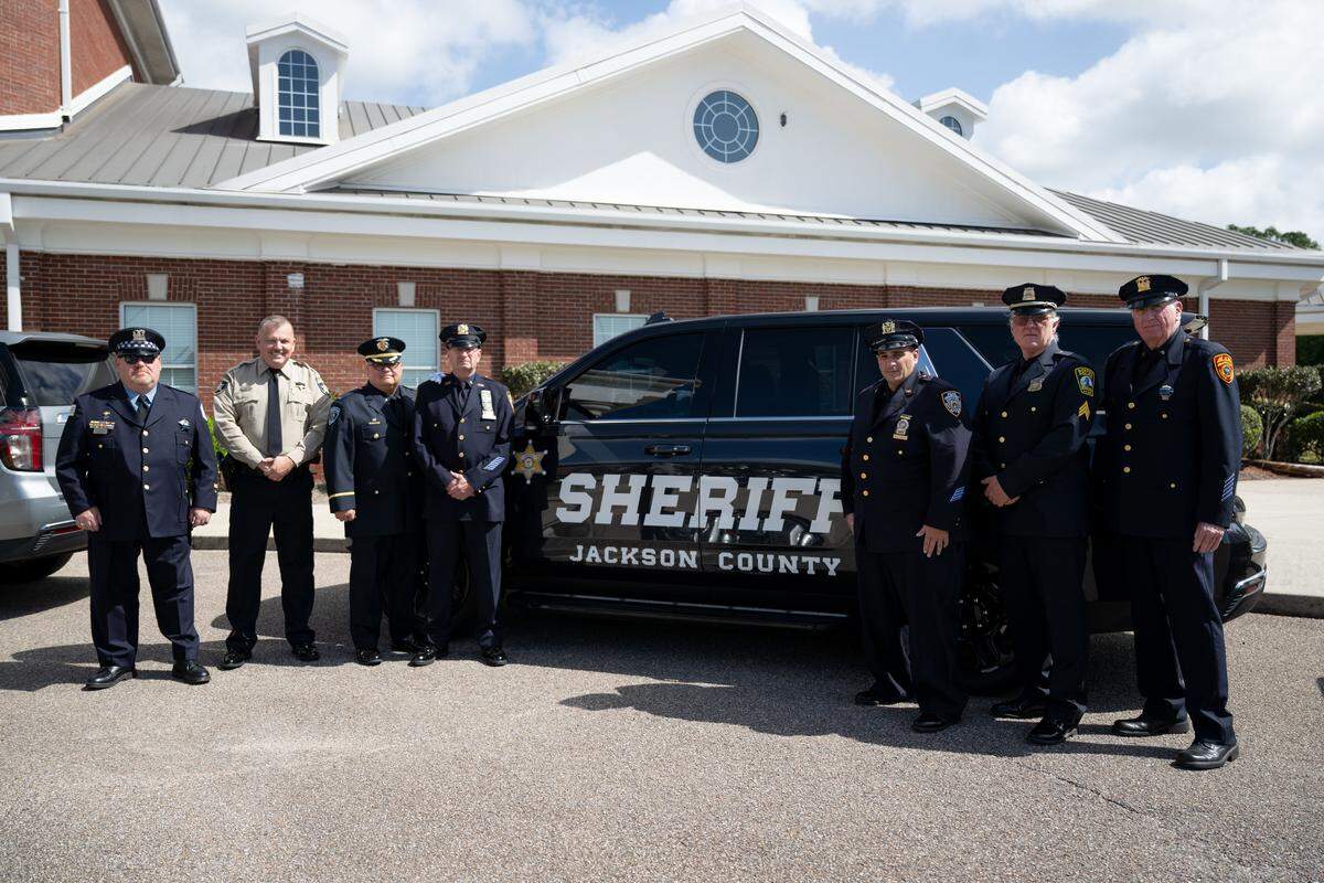 Detectives and police officers with the Brotherhood for the Fallen pose for a photo in front of a Jackson County Sheriff’s Department SUV before the funeral of sheriff’s Deputy Michael Jimerson at the First Baptist Church in Biloxi on Friday, April 10, 2026.