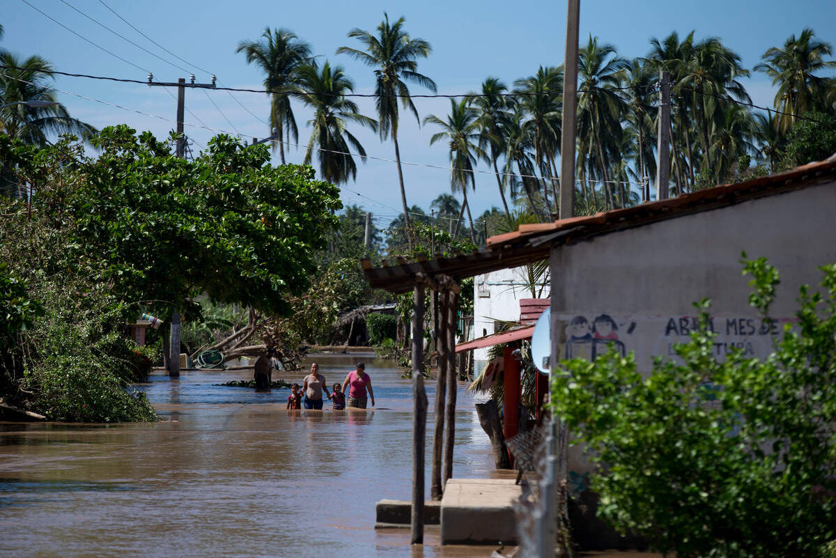 Residents wade down a street through receding floodwaters, two days after Hurricane Patricia in Mexico in 2015.