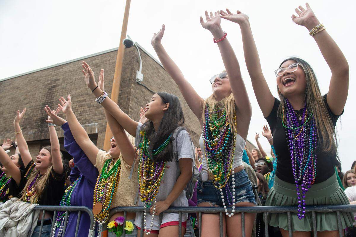 Parade watchers cheer for beads and other throws during the Gulf Coast Carnival Association Mardi Gras parade in Biloxi on Tuesday, March 4, 2025.