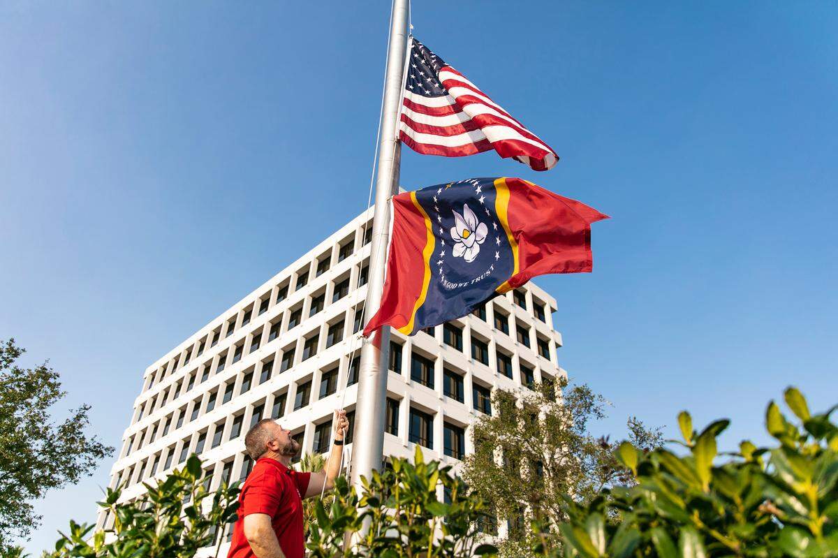 Chris Loposser, who is with Corporate Security at Mississippi Power, raises the “In God We Trust,” or new magnolia flag, outside the company’s offices in downtown Gulfport.