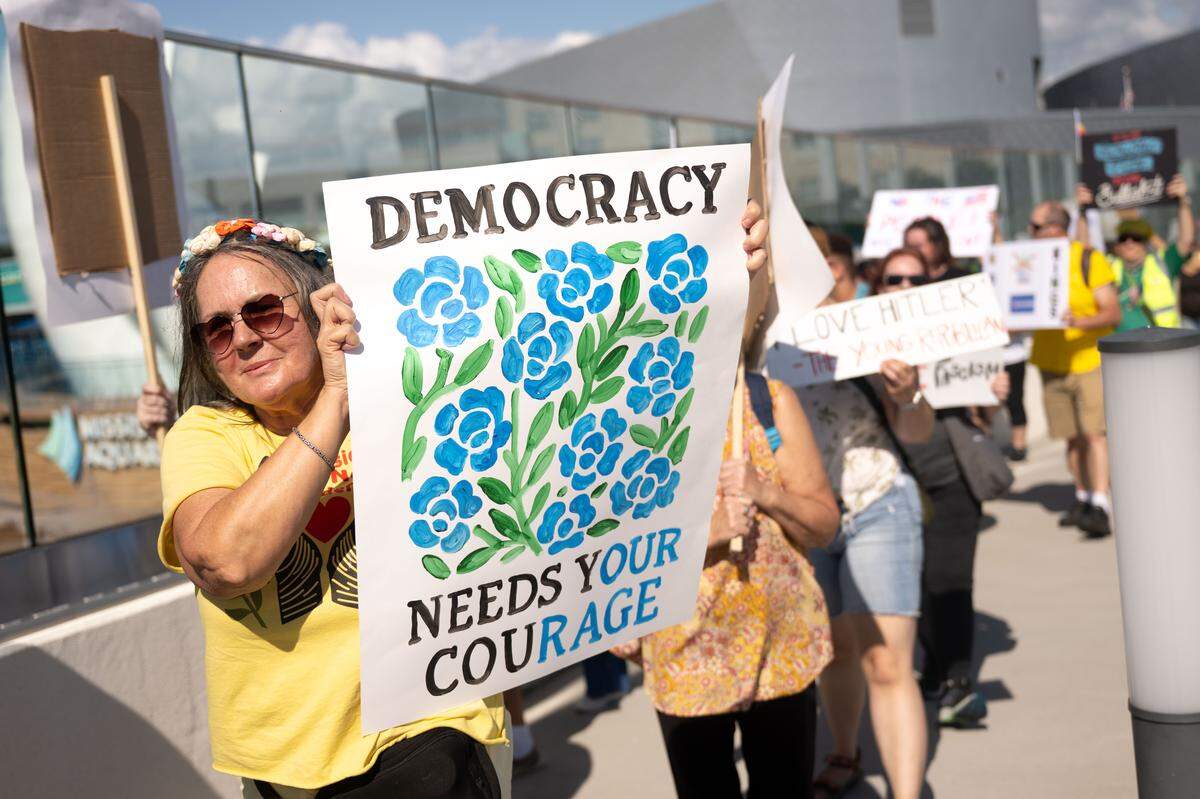 Protesters carry banners and signs across a bridge to Jones Park during a No Kings protest Saturday in Gulfport.