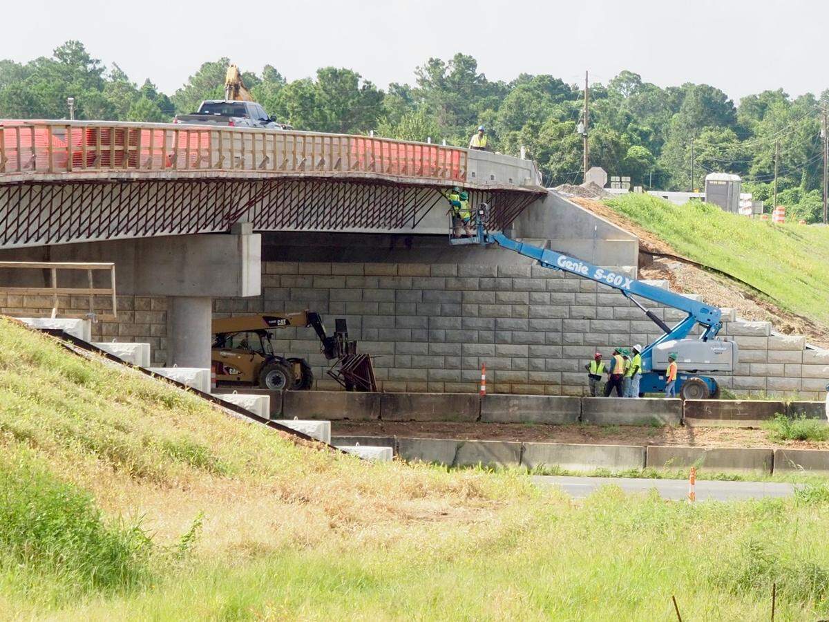 While ground crew looks on from below and a monitor watches from above, T. L. Wallace employees dismantle the catwalk used to support workers installing the side walls of the new Menge Avenue overpass near the Buc-ee’s travel center in Harrison County. The bridge and Exit 24 were redesigned and rebuilt to accommodate the traffic going to Buc-ee’s and other business that will follow.