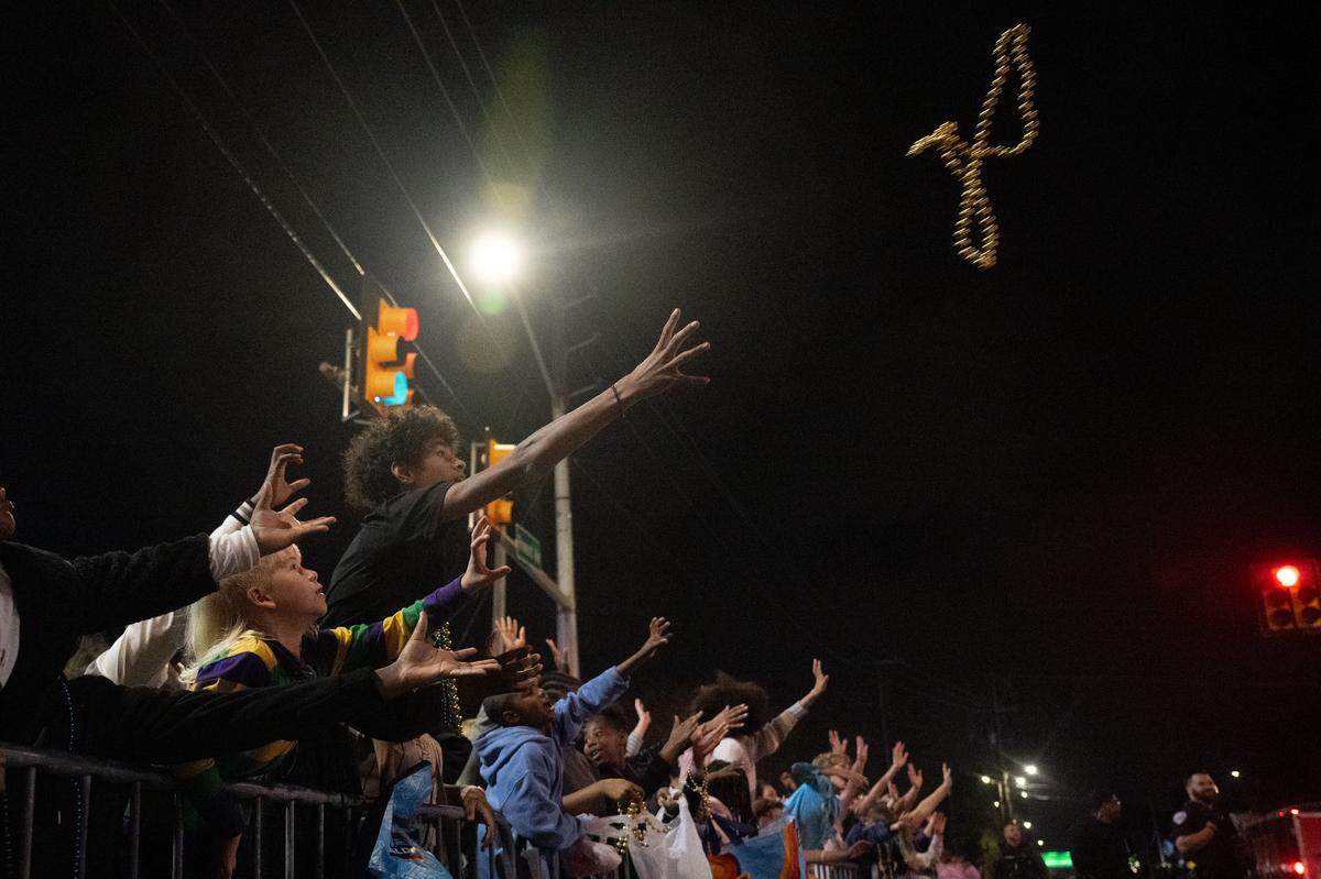 Parade attendees catch Mardi Gras beads during the Krewe of Neptune parade in Biloxi on Saturday, Feb. 14, 2026.