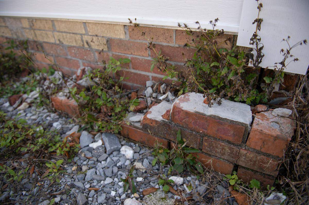 A few bricks are all that remains of the original exterior wall of Milton Grishman’s real estate office in Biloxi on Wednesday, Feb. 9, 2022. The original brick was replaced with the shingles behind it during work on the infrastructure project after it became apparent the brick may fall into the road due to the building shifting from the road work.