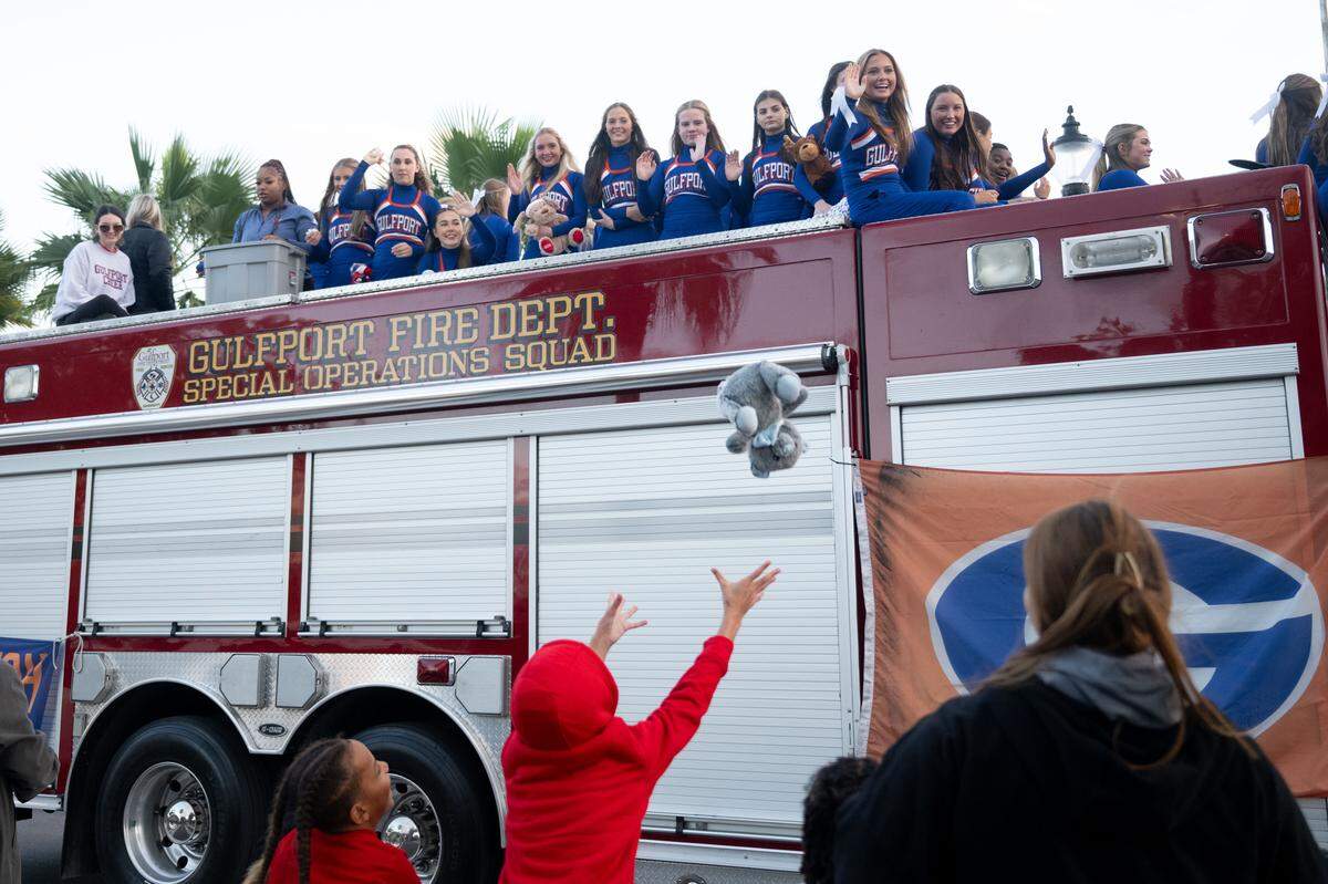 Gulfport cheerleaders toss toys to children during the Champions Christmas Parade in Gulfport on Monday, Dec. 8, 2025.