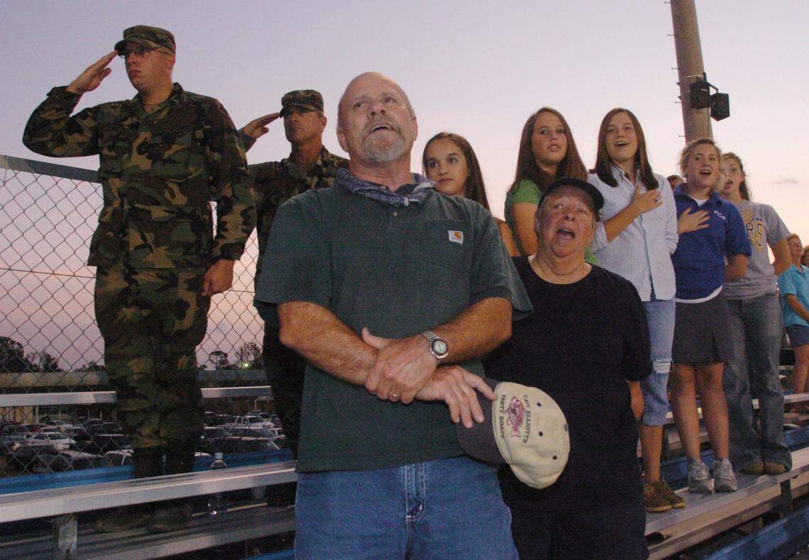 Billy Kidd of Grand Prarie, Tx., and Sandra West of Bay St. Louis sing the National Anthem along with members of visiting military and Bay High students before a game between Bay St. Louis and Long Beach in 2005. Kidd was in town helping West clean her property after Hurricane Katrina.