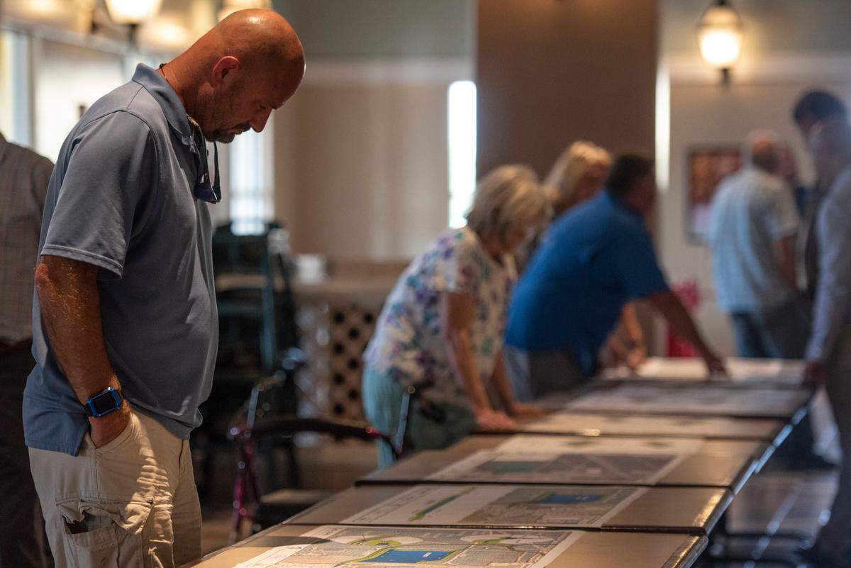 Members of the public look at renderings of a proposed road project west of Highway 49 made by Neel Schaffer, the contracting company developing the project, during a public hearing on the road project at Gulfport Premium Outlets in Gulfport on Wednesday, July 13, 2022.