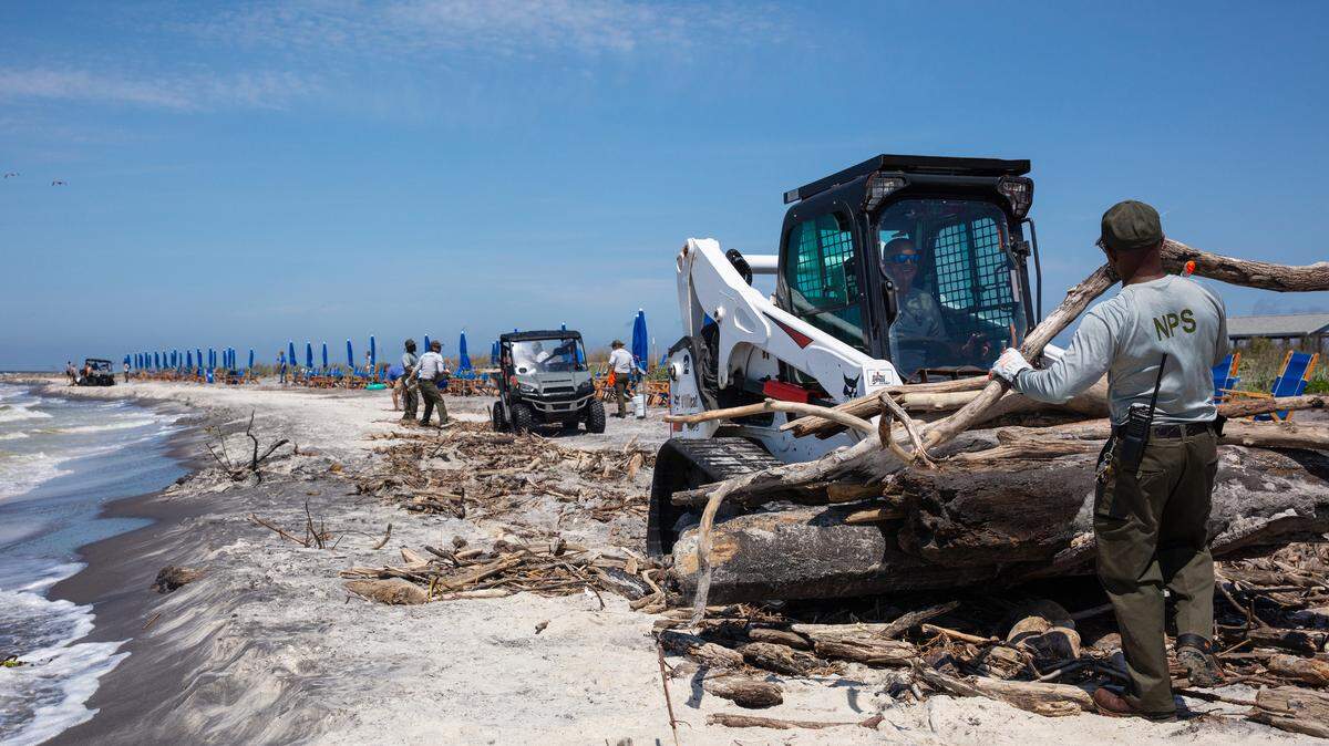 A National Park Service employee picks up heavy debris that Mississippi River flooding washed up recently on the south side of Ship Island, The park service worked with employees of Ship Island Excursions ferry service out of Gulfport to get the beach cleaned up ahead of the Memorial Day weekend.