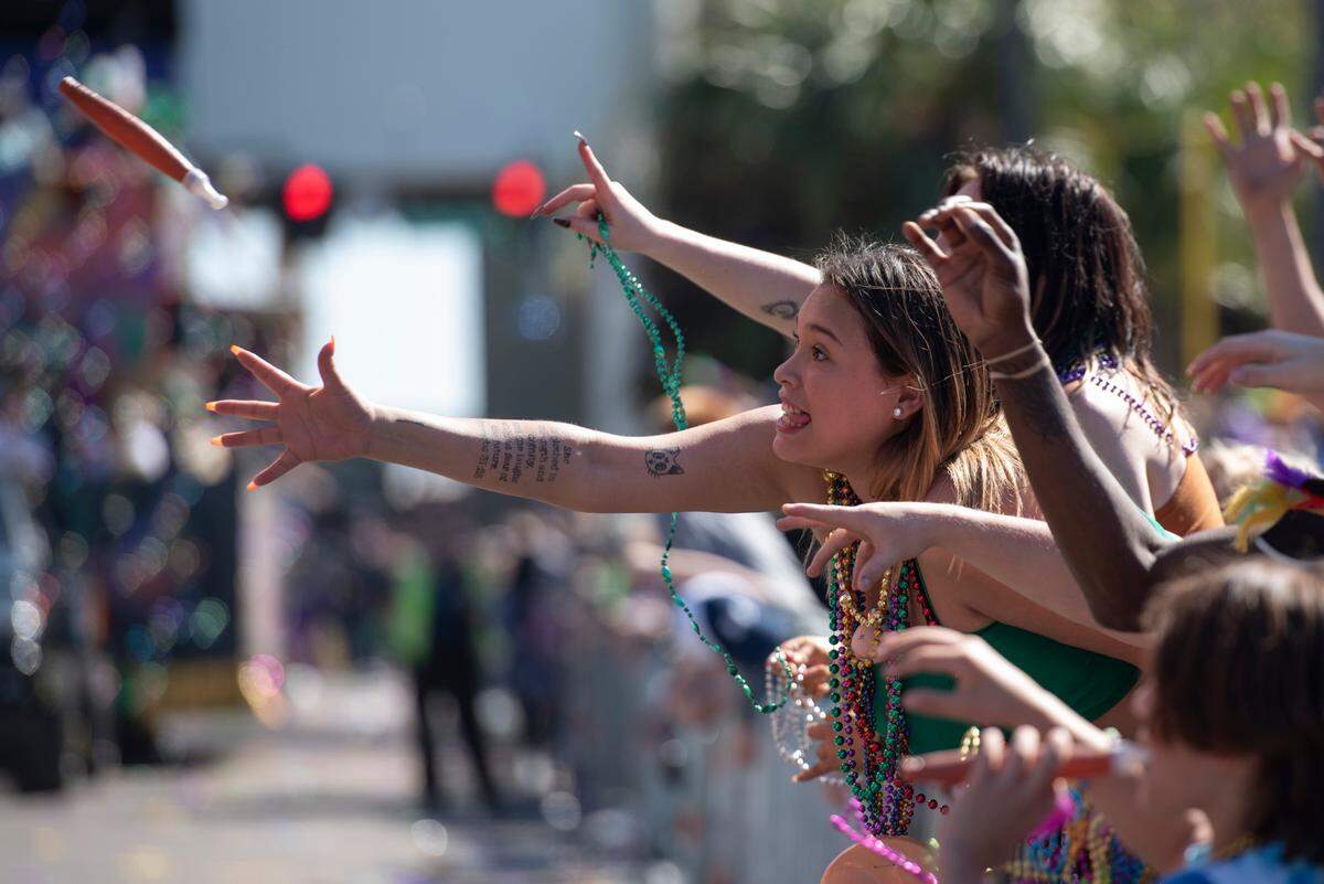 People catch plastic toys thrown from floats during the Gulf Coast Carnival Association Mardi Gras Parade in Biloxi on Tuesday, March 1, 2022.
