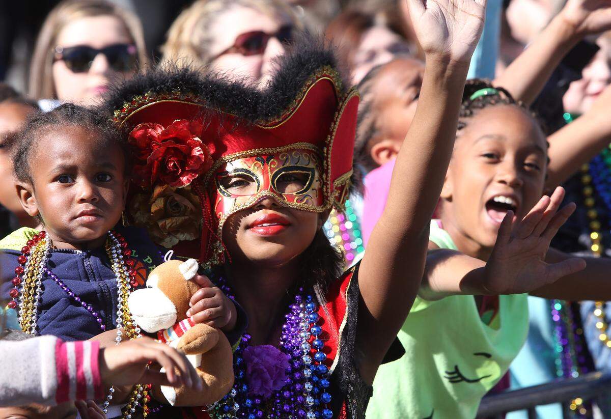 JOHN FITZHUGH/SUN HERALDBrianna Adams of Gulfport calls for throws as she holds her godson Ataurian Adama, 1, during the Gulf Coast Carnival Association Mardi Gras Parade in Biloxi on Tuesday Feb. 9, 2016.