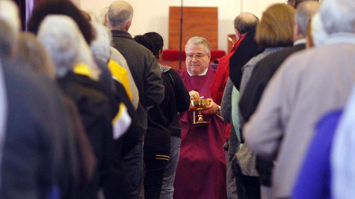 Prior to placing the ashes, Father George Kitchin conducts communion at St. James Catholic Church in 2013.