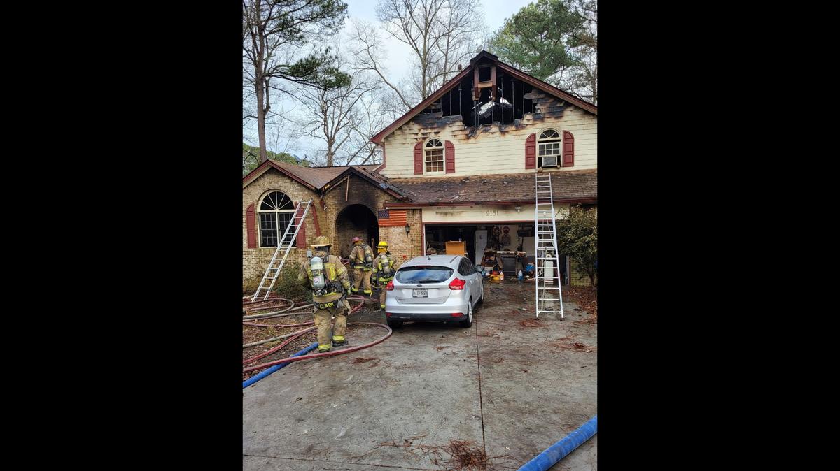 A neighbor called 911 to report a house fire as her boyfriend ran in to help the resident and her dog escape the New Year’s Eve blaze, Georgia fire officials said. 