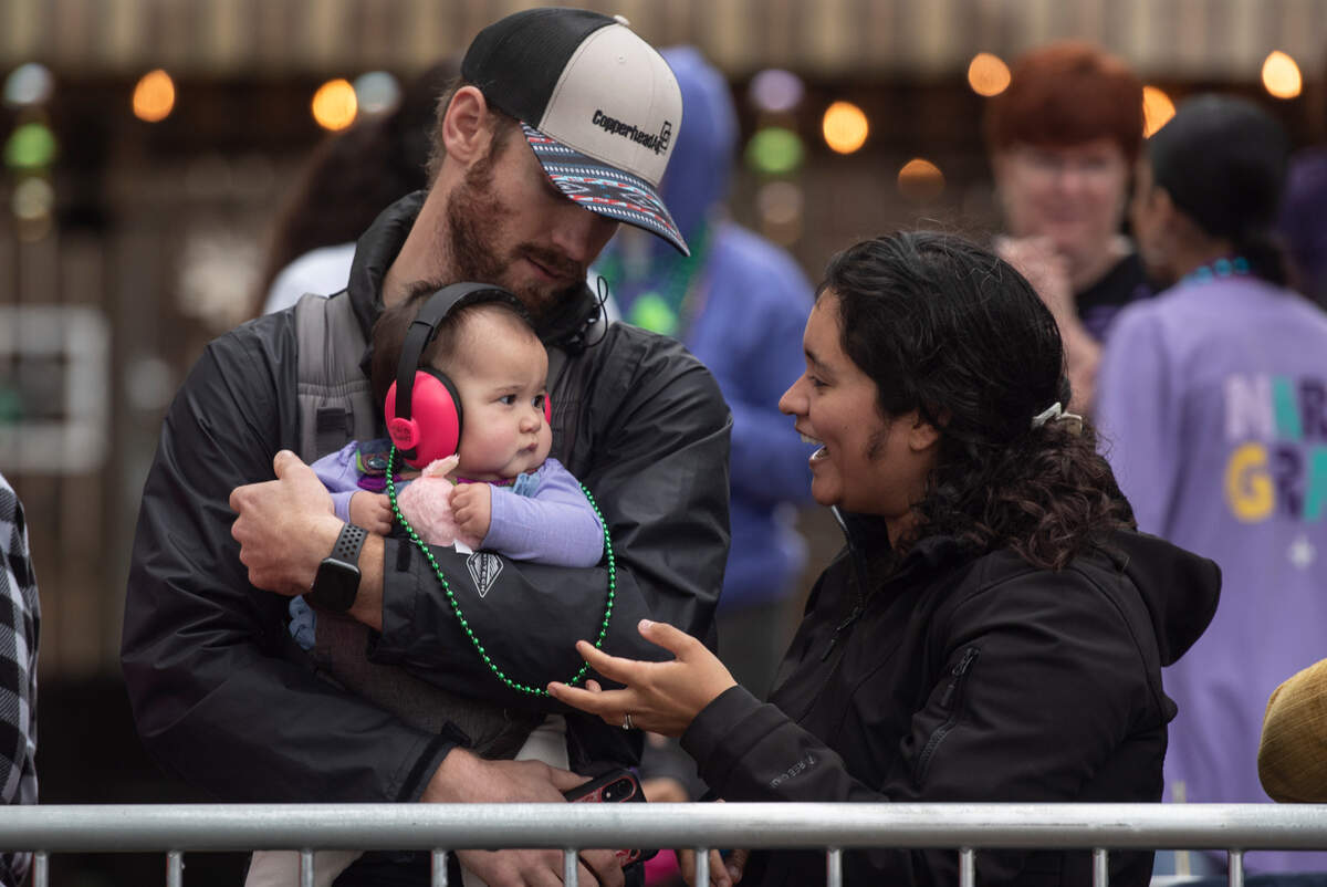 A family puts a string of beads around their baby during the Ocean Springs Elks Carnival Parade in downtown Ocean Springs on Saturday, Jan. 27, 2024.