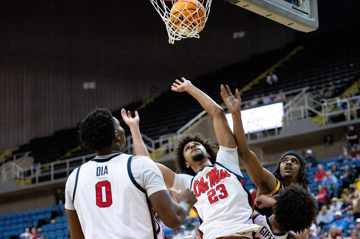 Mississippi and Southern Mississippi players jump at the basket in hopes of hauling in a rebound.