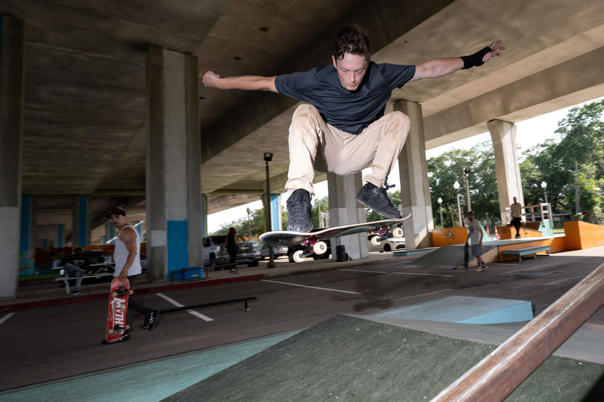 Chris Jobes performs a jump over a ramp with his skateboard.