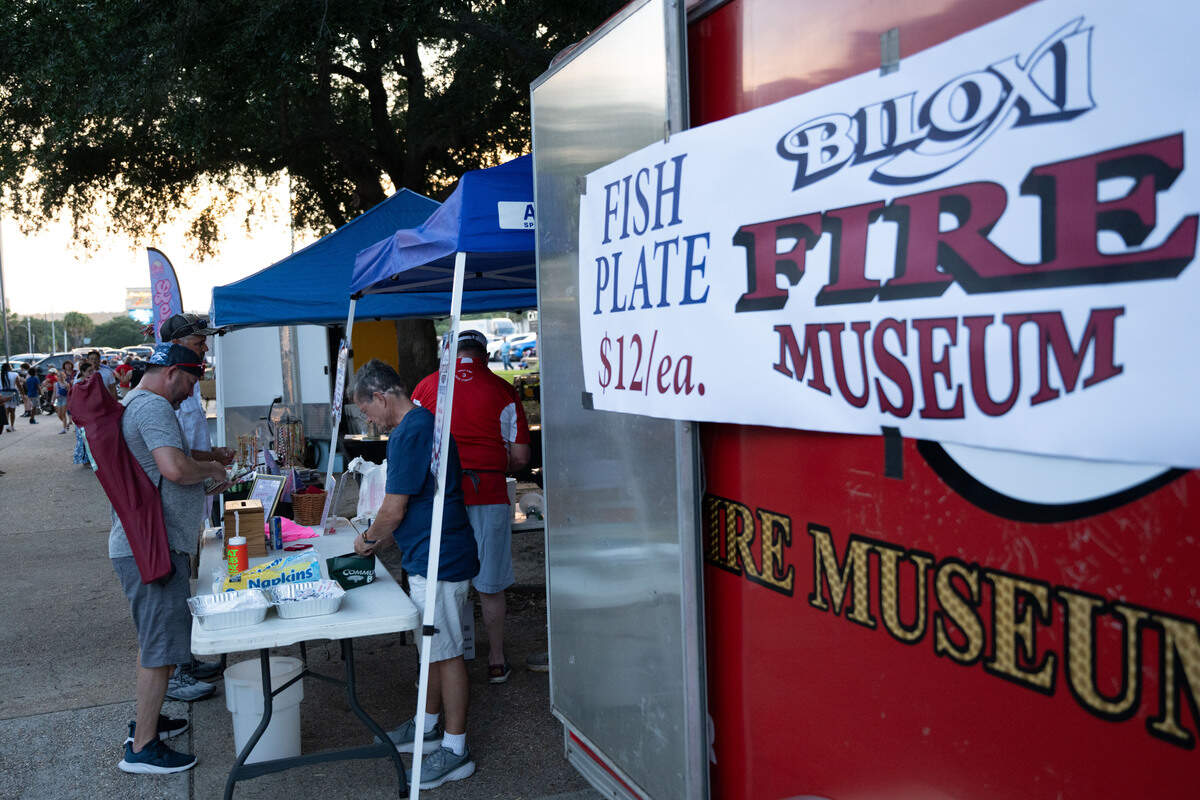 Event attendees purchase a fish plate from a food stand by the Biloxi Fire Museum during a Fourth of July show at the Biloxi Town Green on Saturday, July 4, 2026.