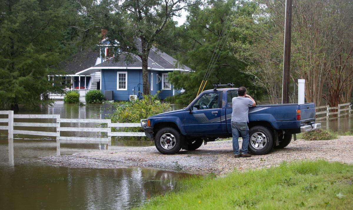 A groundskeeper surveys the damage of a historic home in Kiln that is surrounded by Bayou Latterre floodwaters caused from storm surge by Hurricane Ida on Aug. 30, 2021.
