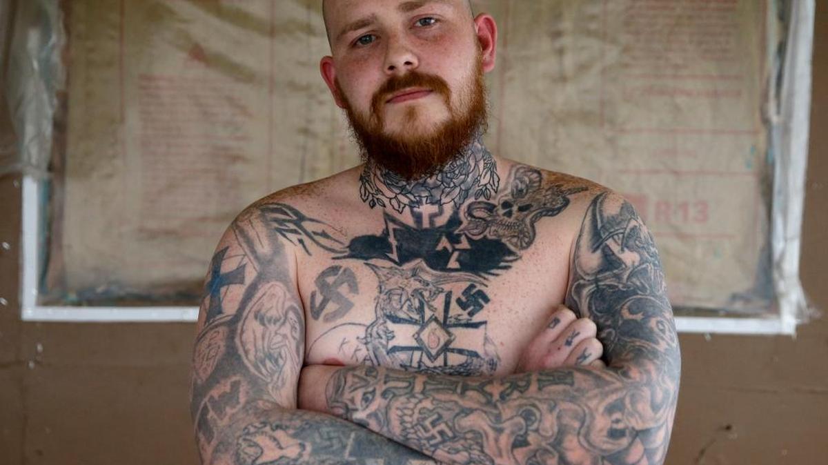 In this Thursday, Jan. 12, 2017 photo, Shane Johnson displays some of his tattoos as he poses in his home in Tippecanoe, Ind. Johnson was born into extremism is in the process of covering some of his racist tattoos with new ones and wears long sleeves to hide remnants of his past he regrets. His father and many of his father's relatives were part of the Klan, he said, so there was only one real way for him to go as a youth.