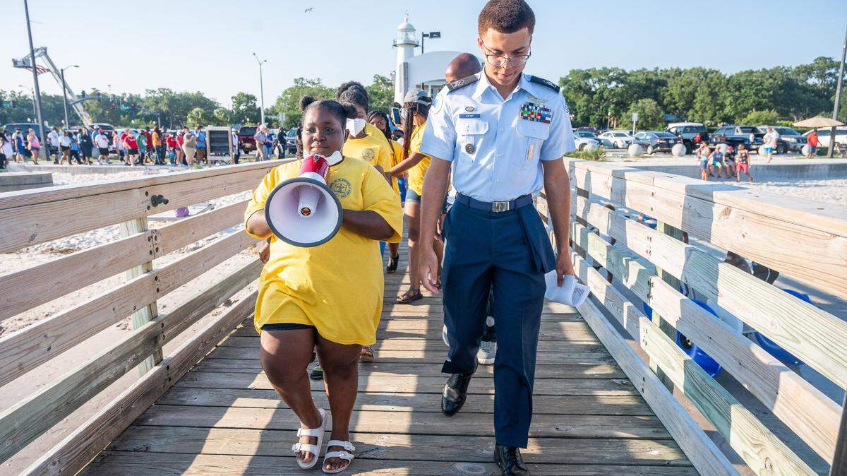 An American flag hangs from a firetruck over Highway 90 as Jaelynn Burden and Savéair Kemp lead the Biloxi wade-in reenactment down the Lighthouse Pier boardwalk on Saturday, June 20, 2020.