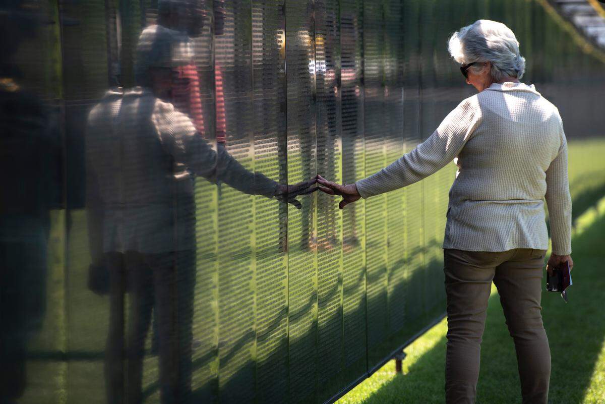 Visitors look at names on The Wall That Heals, a traveling three-quarter scale replica of the Vietnam Veterans Memorial in D.C., while it is on display at the D’Iberville Sports Complex in D’Iberville on Thursday, April 10, 2025.