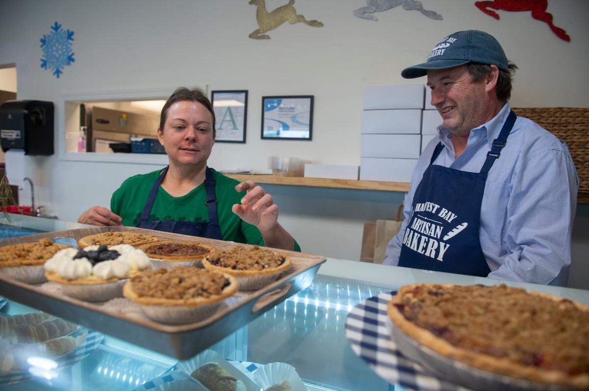 Owner Alex Lacy and baker Brooke Craig show off different pies for sale at Harvest Bay Artisan Bakery in Bay St. Louis on Thursday, Dec. 7, 2023.
