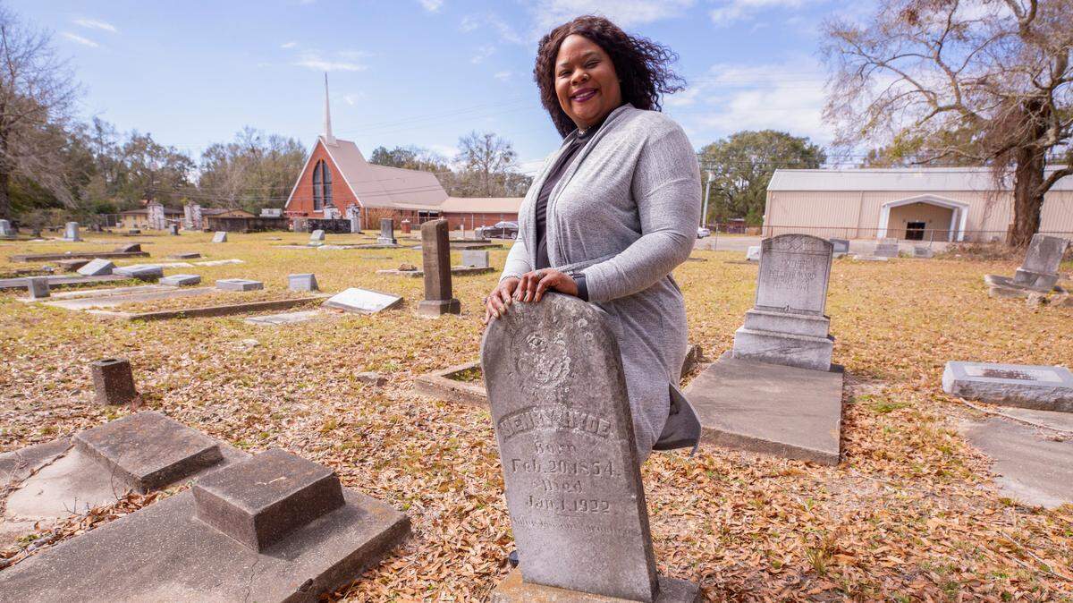 Melissa Evans stands with the grave of her oldest family member, Henry Hyde born in 1854, at St. Paul Cemetery in Moss Point, Miss.