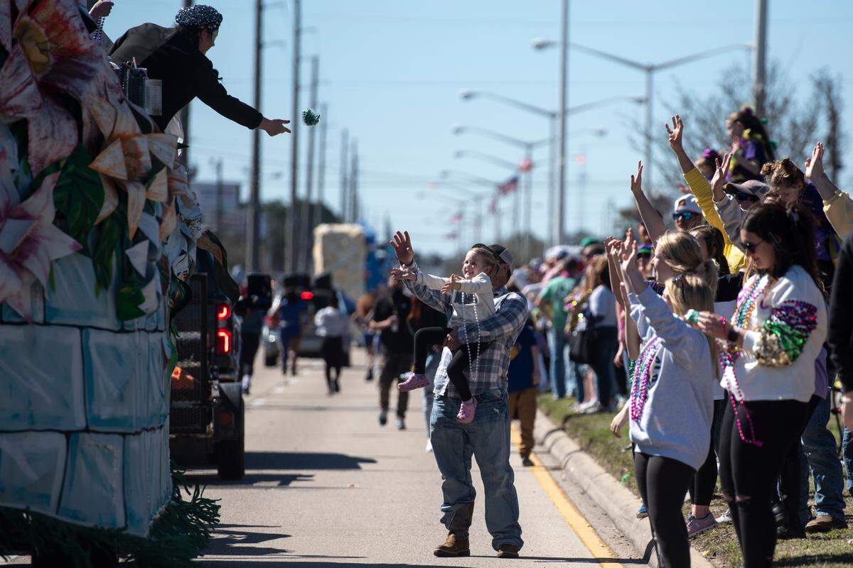 Crowds cheer for beads to be tossed in their direction during the Krewe of Nereids Mardi Gras parade on Highway 90 in Bay St. Louis on Sunday, Feb. 12, 2023.