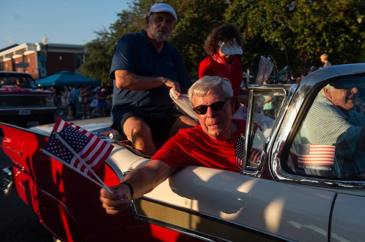 Cruisers pass out flags and throws during the Long Beach Parade in Long Beach, one of the events in Cruisin’ The Coast, on Monday, Oct. 7, 2024.
