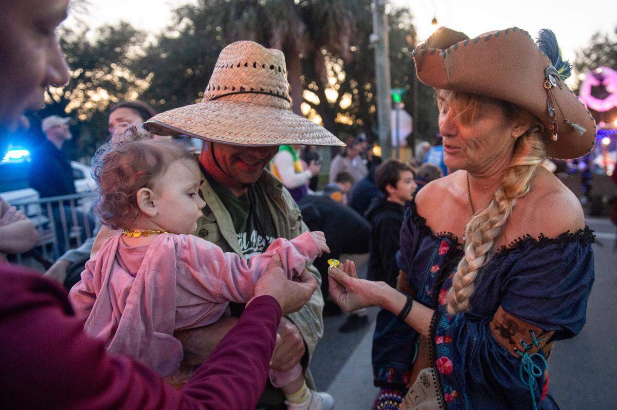 A member of Mystic Krewe of the Seahorse hands out rings during the krewe’s Lundi Gras parade in Bay St. Louis on Monday, March 3, 2025.