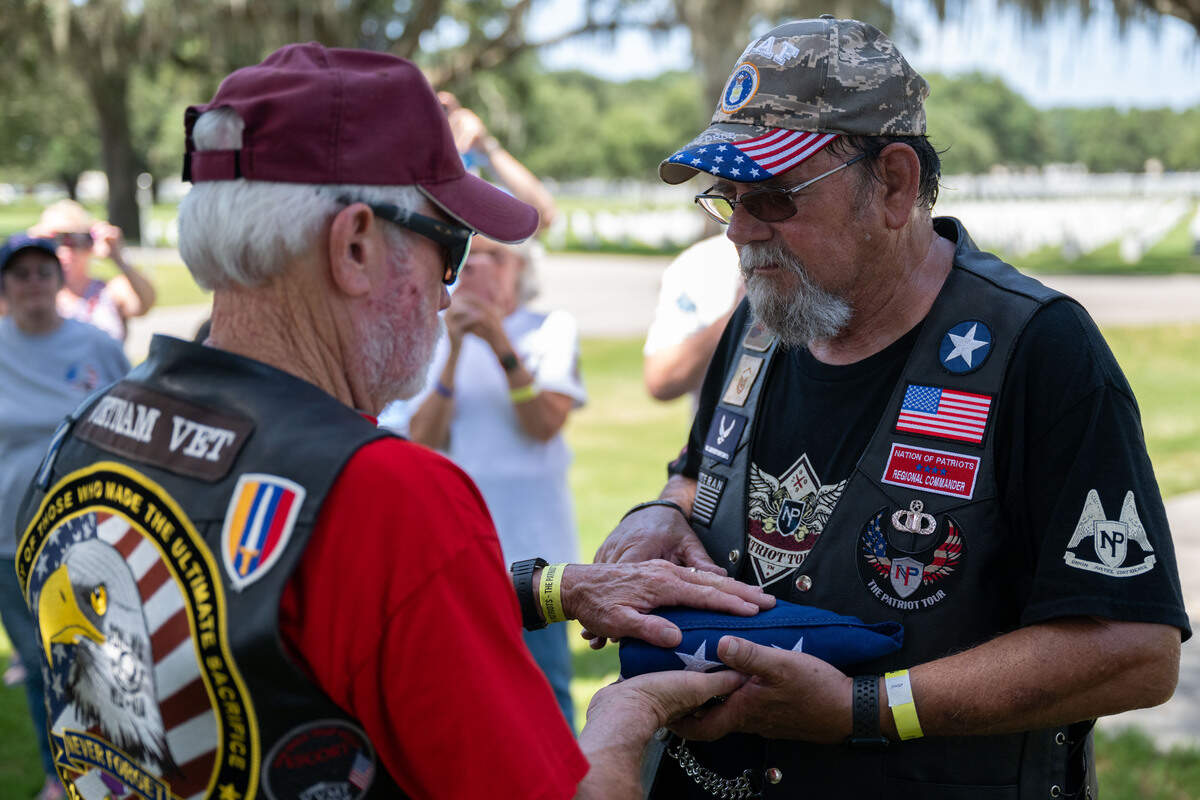 Gerald Hagan, left, passes the American flag to Steve Carrington during a ceremony at Biloxi National Cemetery on Saturday, July 11, 2026.