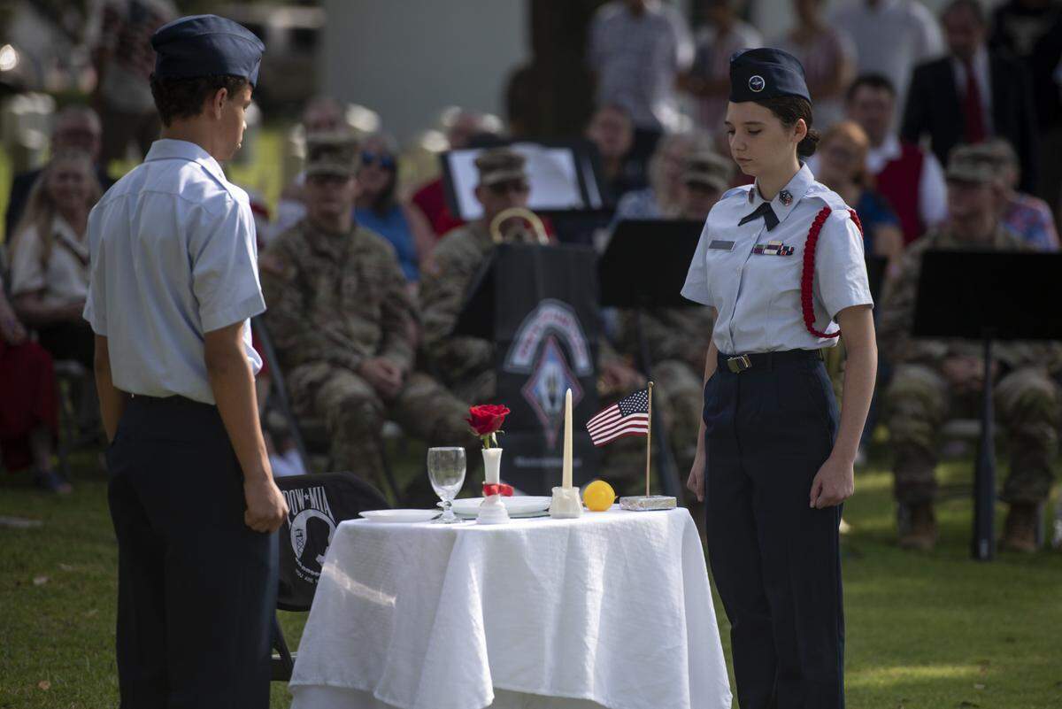 Civil Air Patrol members stand beside a table representing prisoners of war and those killed in action during a Memorial Day ceremony at Biloxi National Cemetery in Biloxi on Monday, May 26, 2025.