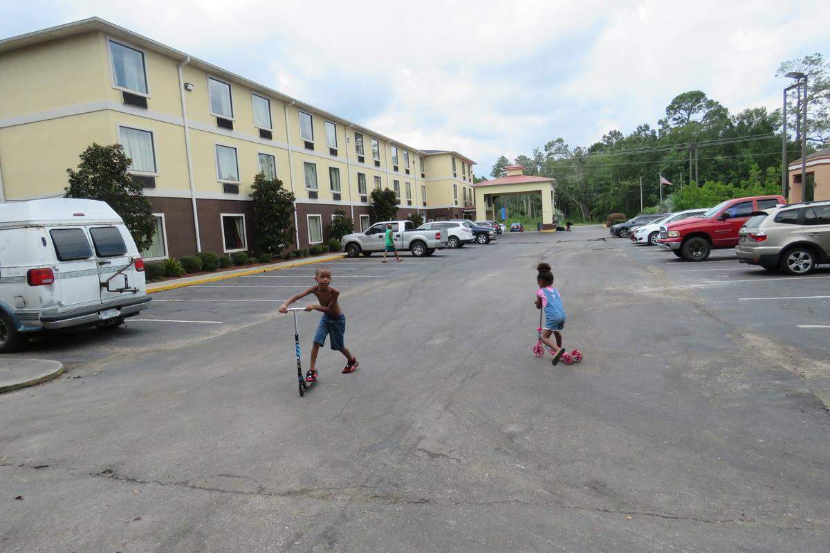 Samantha Dees’ 7-year-old son and 4-year-old daughter play on their scooters in the parking lot of the Motel 6 where they’ve been living since April 2021, on Saturday, Sept. 4, 2021.