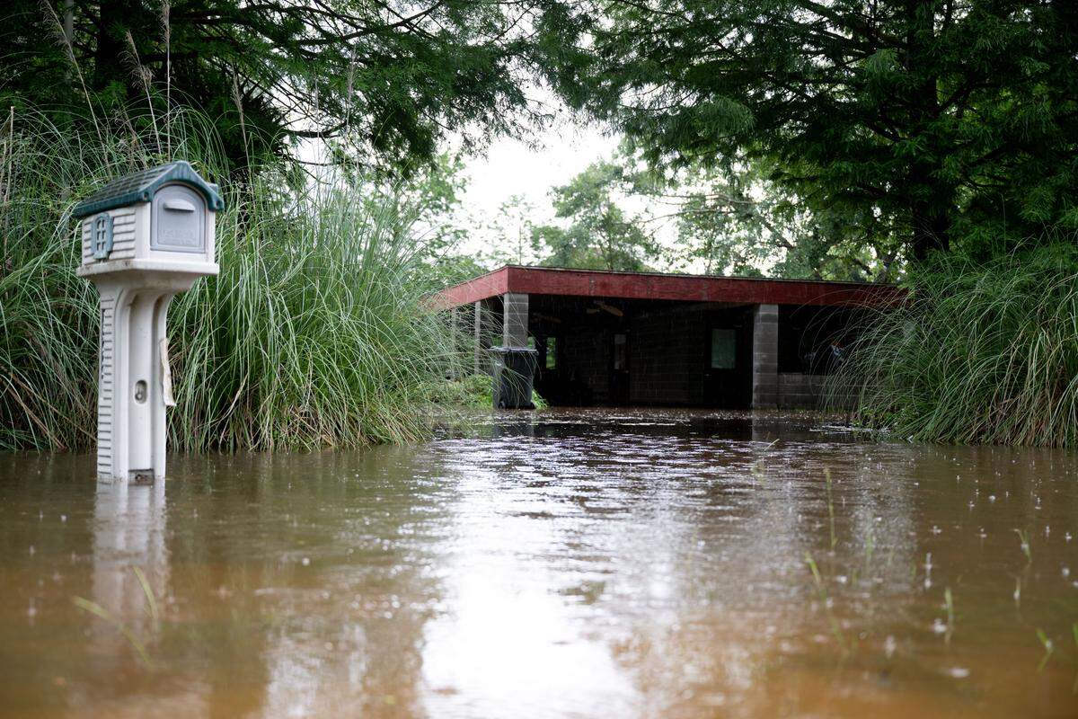 A single floor house is surrounded by the Jourdan River along Highway 603 in Kiln on Tuesday.